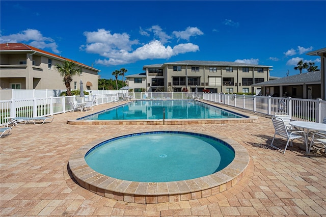 community pool featuring a community hot tub, a patio area, and fence