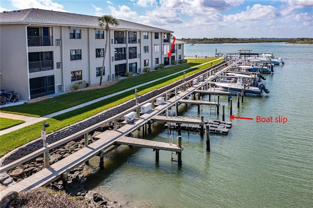 dock area with boat lift, a yard, and a water view