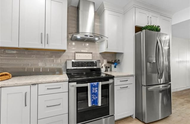 kitchen featuring stainless steel appliances, tasteful backsplash, white cabinets, and wall chimney range hood