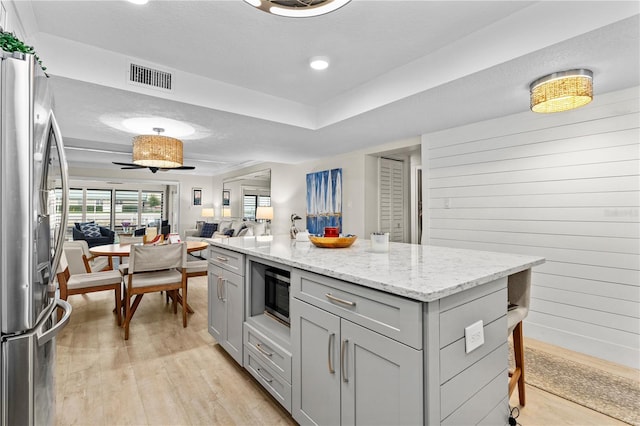 kitchen with stainless steel appliances, light wood-style floors, gray cabinetry, and visible vents