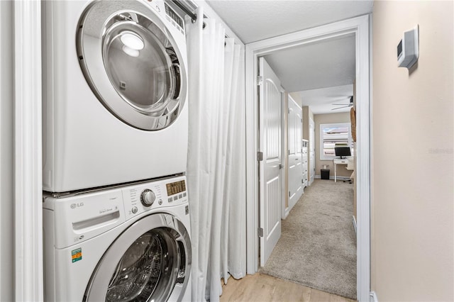 laundry room with stacked washer / drying machine, light colored carpet, ceiling fan, and laundry area