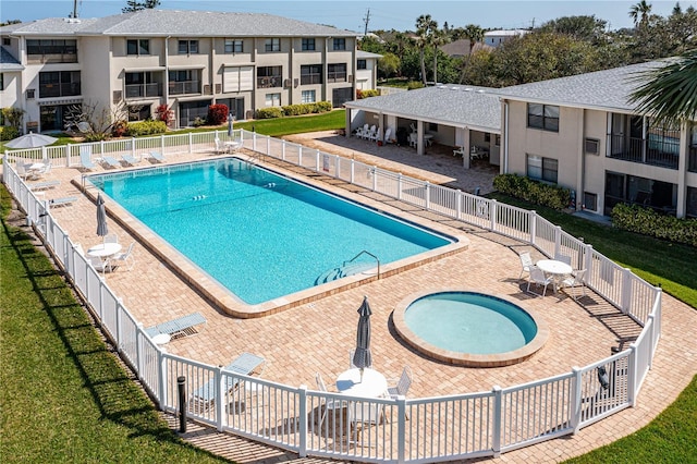 community pool featuring a yard, fence, a patio area, and a hot tub