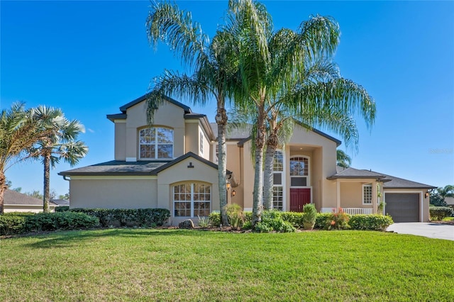 mediterranean / spanish home with a front yard, concrete driveway, an attached garage, and stucco siding