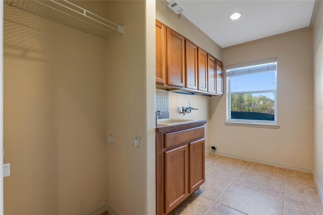 laundry area featuring light tile patterned floors, washer hookup, a sink, baseboards, and cabinet space