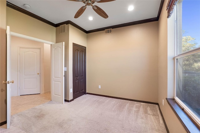 empty room featuring ornamental molding, light carpet, visible vents, and baseboards