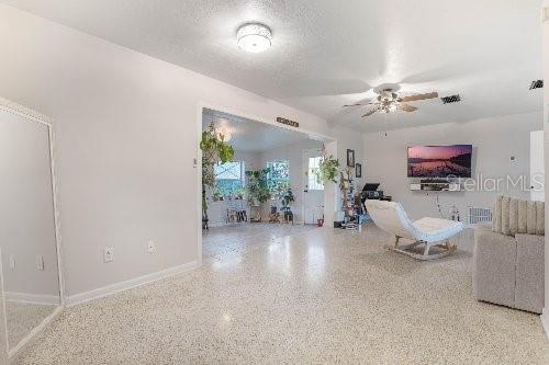 unfurnished living room with ceiling fan and a textured ceiling