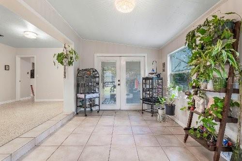 entryway featuring light tile patterned flooring, lofted ceiling, and french doors