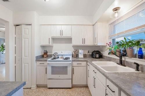 kitchen featuring white cabinets, sink, and white range oven