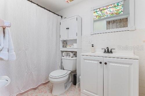 bathroom featuring vanity, tile walls, toilet, and a shower with shower curtain