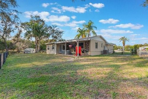 rear view of property featuring cooling unit and a yard