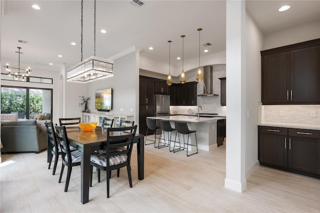 dining area featuring a notable chandelier, crown molding, and light wood-type flooring