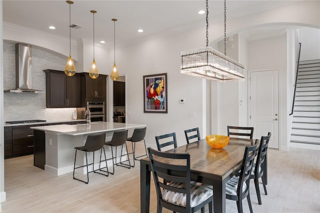 dining space featuring crown molding, light hardwood / wood-style flooring, and a high ceiling