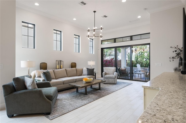 living room featuring an inviting chandelier, ornamental molding, light hardwood / wood-style floors, and a high ceiling