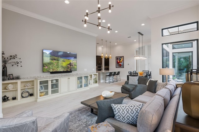 living room with crown molding, a chandelier, and light hardwood / wood-style floors