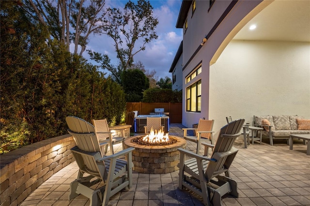 patio terrace at dusk with an outdoor living space with a fire pit