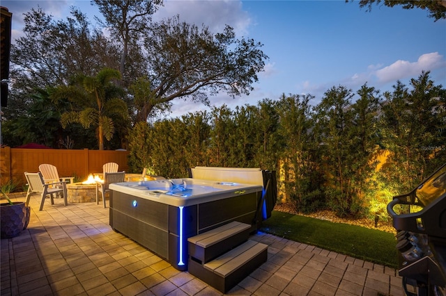 patio terrace at dusk featuring a hot tub and a fire pit