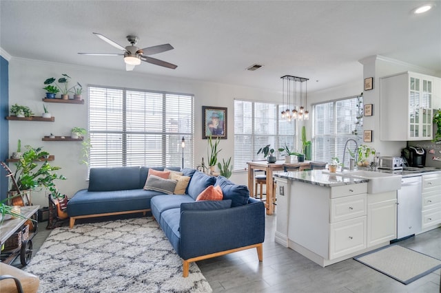 kitchen with sink, decorative light fixtures, stainless steel dishwasher, ornamental molding, and white cabinets