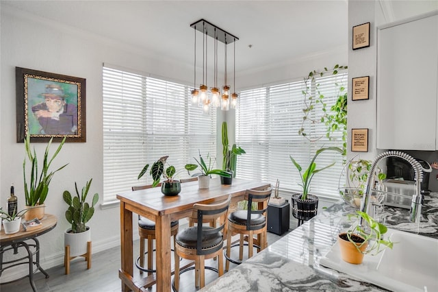 dining room with a notable chandelier, plenty of natural light, ornamental molding, and light wood-type flooring