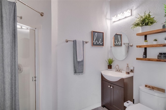 bathroom with vanity, toilet, and a shower with door