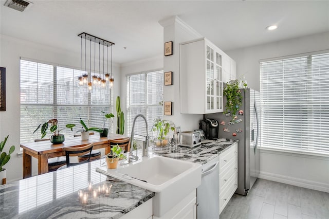 kitchen with sink, hanging light fixtures, dishwasher, dark stone counters, and white cabinets