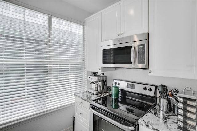 kitchen with light stone countertops, stainless steel appliances, and white cabinets