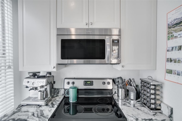 kitchen with white cabinetry, light stone countertops, and appliances with stainless steel finishes