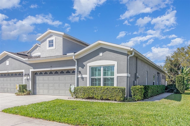 view of front facade with a garage, a front yard, driveway, and stucco siding