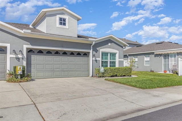 view of front of house featuring a front yard, concrete driveway, an attached garage, and stucco siding