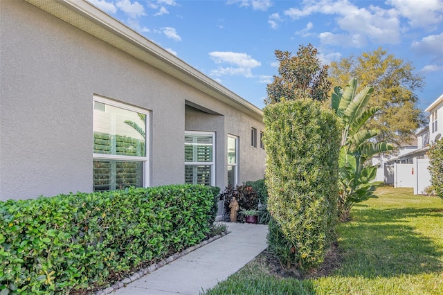 doorway to property featuring a lawn and stucco siding