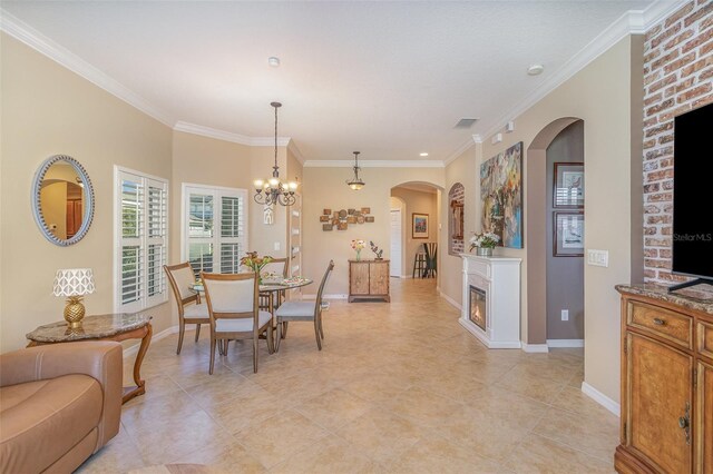 dining area featuring a lit fireplace, baseboards, and crown molding