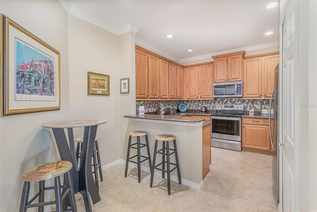 kitchen featuring a breakfast bar area, stainless steel appliances, a peninsula, ornamental molding, and backsplash