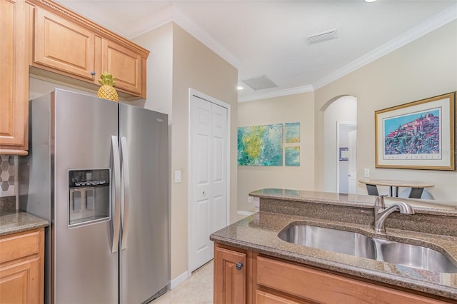 kitchen with visible vents, stainless steel refrigerator with ice dispenser, a sink, and dark stone counters