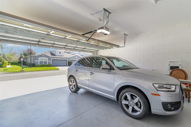 garage featuring concrete block wall and a garage door opener