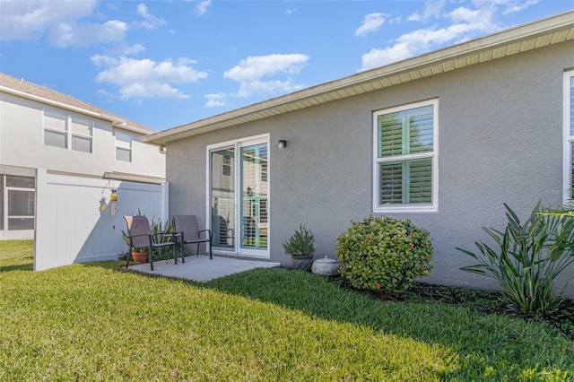 back of property with a yard, a patio area, and stucco siding