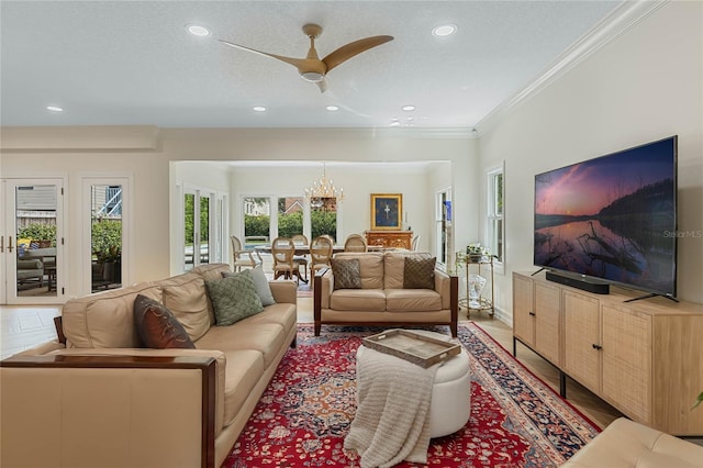 living room with crown molding, ceiling fan with notable chandelier, and a textured ceiling