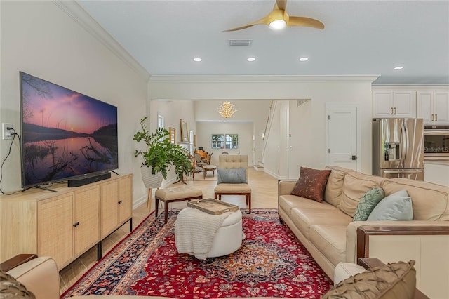 living room featuring light hardwood / wood-style flooring, crown molding, and ceiling fan with notable chandelier