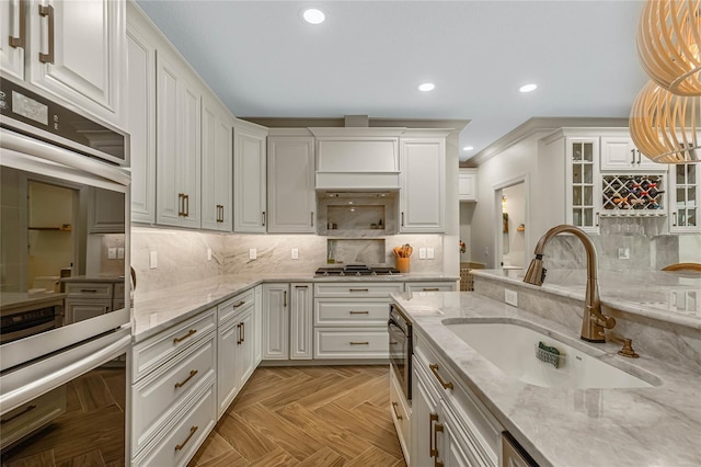 kitchen featuring sink, white cabinets, hanging light fixtures, stainless steel appliances, and light parquet flooring