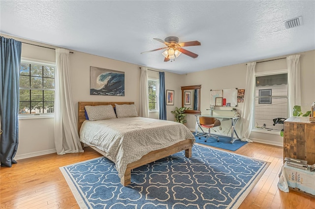 bedroom with ceiling fan, a textured ceiling, and light wood-type flooring