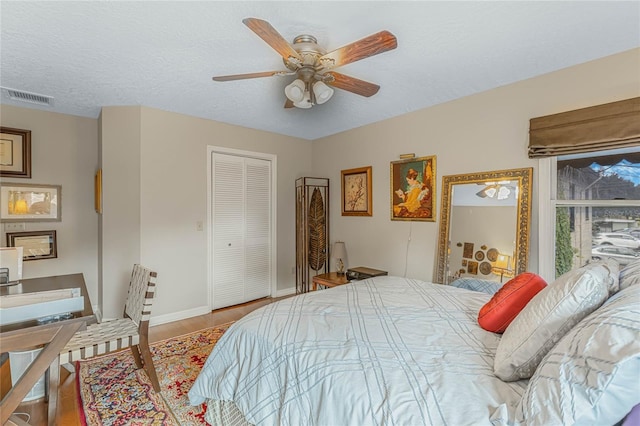 bedroom with ceiling fan, a closet, a textured ceiling, and light wood-type flooring