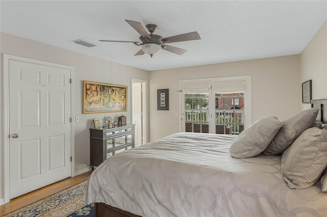 bedroom with ceiling fan, hardwood / wood-style floors, a textured ceiling, and access to outside