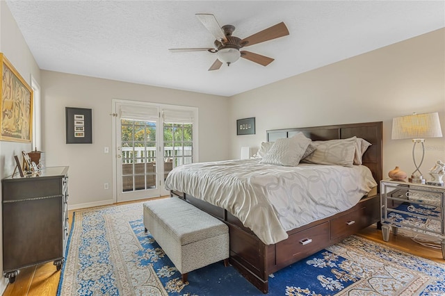 bedroom with hardwood / wood-style flooring, ceiling fan, access to outside, and a textured ceiling