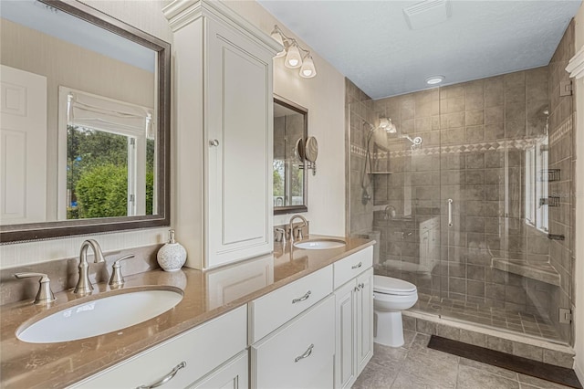 bathroom featuring vanity, walk in shower, toilet, tile patterned floors, and a textured ceiling