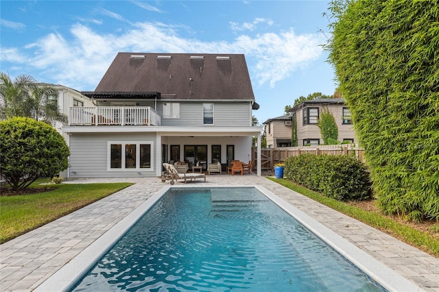 back of property with a fenced in pool, a patio area, outdoor lounge area, and a balcony