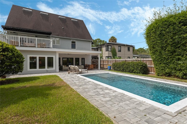 back of house featuring a fenced in pool, a lawn, a patio, an outdoor hangout area, and a balcony