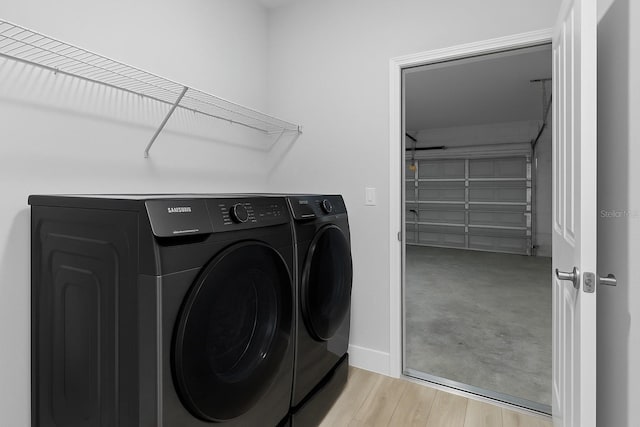 clothes washing area featuring baseboards, laundry area, washer and clothes dryer, and wood finished floors