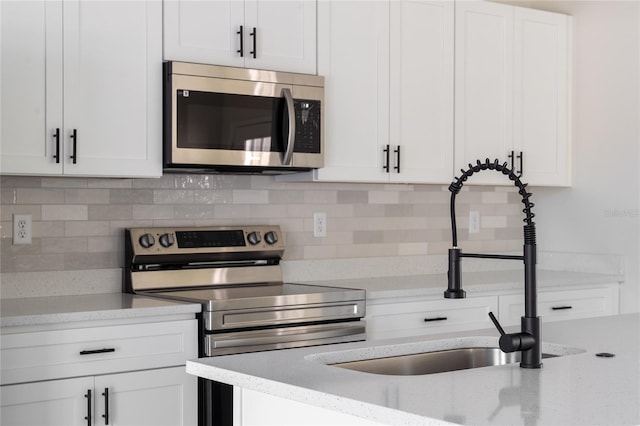 kitchen with a sink, appliances with stainless steel finishes, white cabinets, and tasteful backsplash