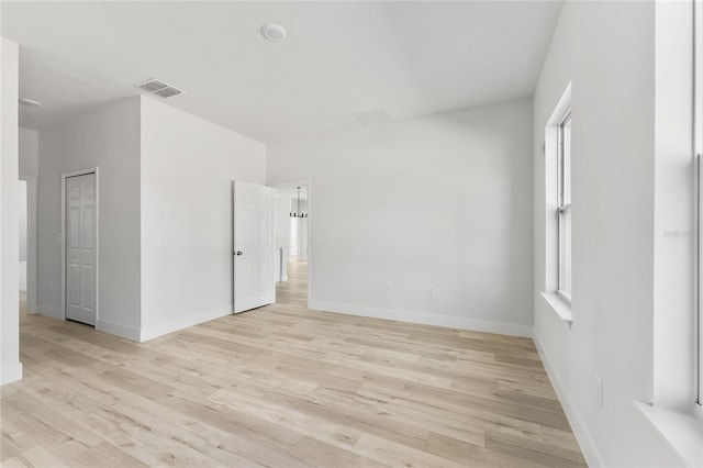 empty room featuring baseboards, visible vents, and light wood-type flooring