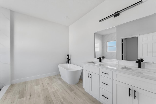 full bathroom with double vanity, a sink, wood finished floors, and a soaking tub