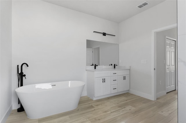 bathroom featuring visible vents, double vanity, and wood finished floors