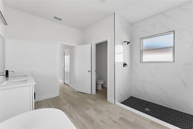 full bath with visible vents, wood finished floors, a sink, toilet, and a marble finish shower